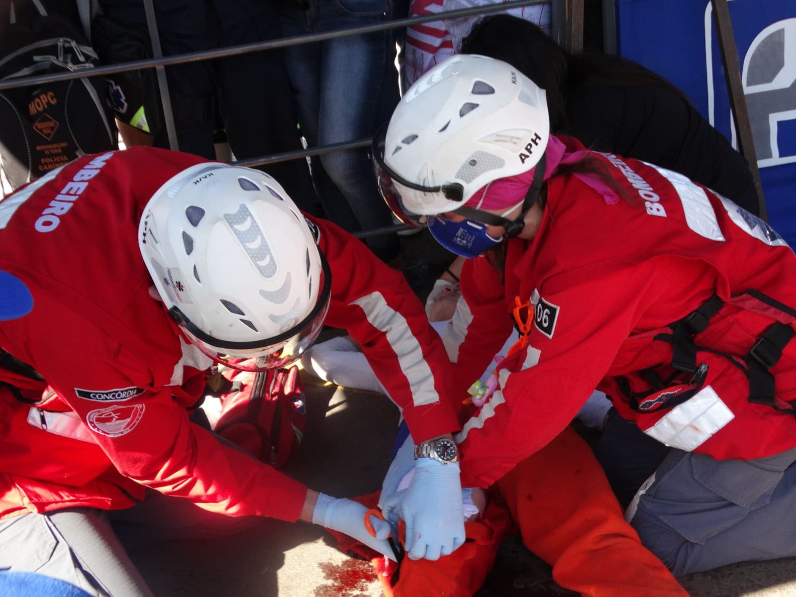Dos rescatistas con casco brindan atención de trauma a una persona en el suelo